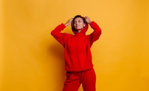 mulher usando conjunto de moletom vermelho em fundo amarelo