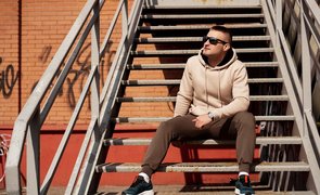 homem sentado em escada com look casual masculino